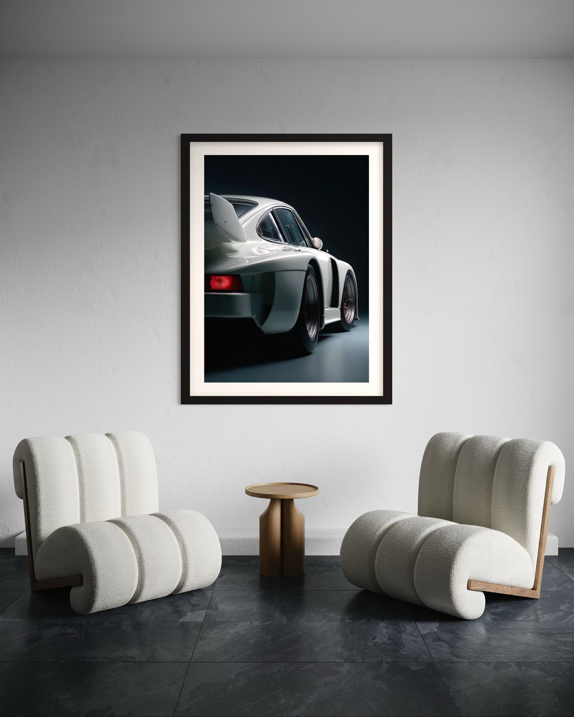 Framed artwork of a white 1980 Porsche 935 sports car on a wall above two modern chairs.